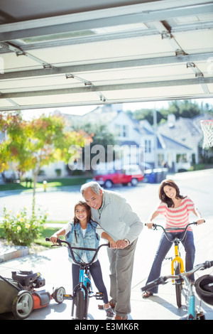 Multi-generation family riding bicycles in driveway Stock Photo