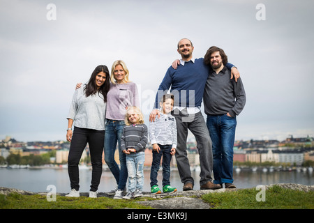 Full length portrait of homosexual families standing together at lakeshore Stock Photo