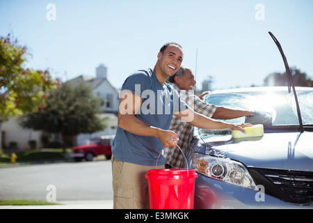 Father and son washing car in driveway