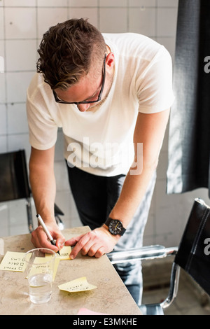 Young businessman writing adhesive notes on desk at new office Stock Photo