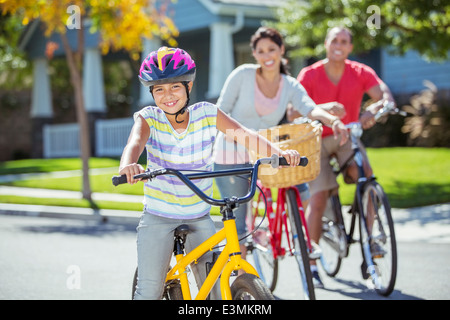 Portrait of smiling family riding bikes in street Stock Photo