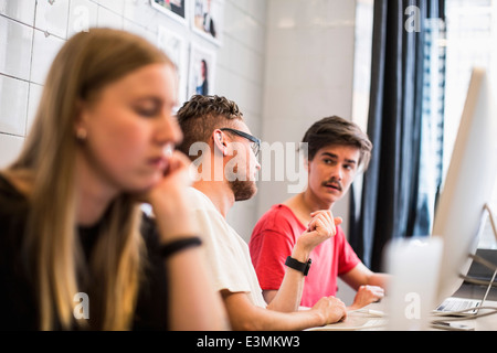 Young businessmen discussing with female colleague working in foreground at new office Stock Photo