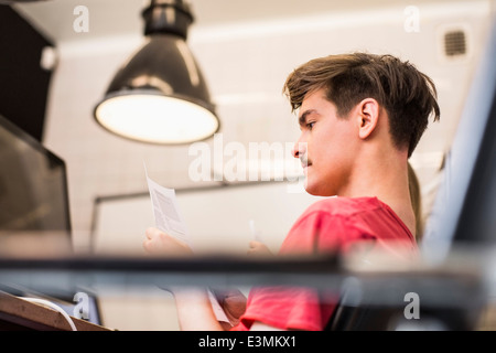 Side view of young businessman reading document in new office Stock Photo