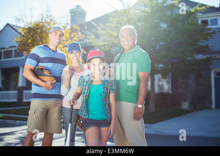 Portrait of smiling multi-generation family with baseball bat in street Stock Photo