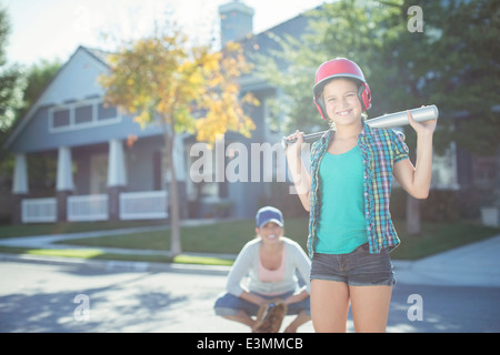 Portrait of mother and daughter playing baseball in street Stock Photo