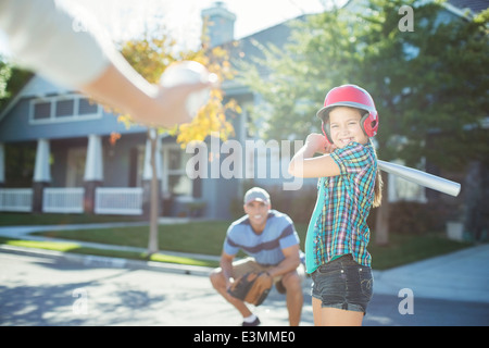Family playing baseball in street Stock Photo