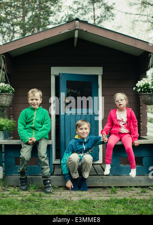 Portrait of siblings sitting on porch Stock Photo