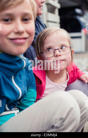 Girl with down syndrome looking at brother outdoors Stock Photo