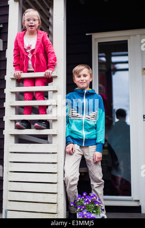 Portrait of brother and sister at porch Stock Photo