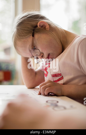 Girl with down syndrome studying at table Stock Photo