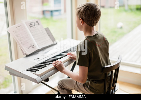 Rear view of boy playing piano at home Stock Photo