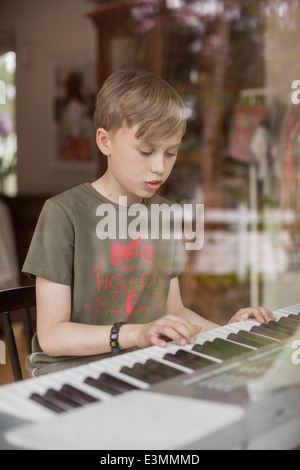 Boy signing while playing piano in house Stock Photo