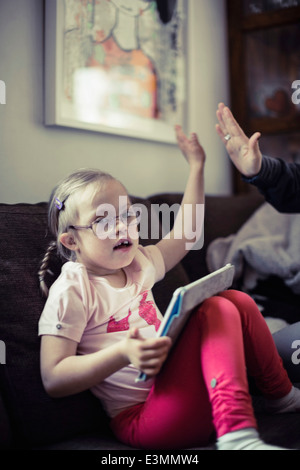 Portrait of girl giving high-five to mother on sofa Stock Photo