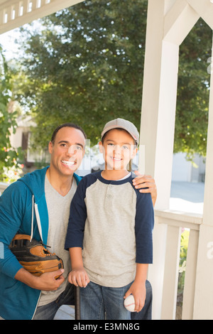 Portrait of father and son with baseball and glove on porch Stock Photo