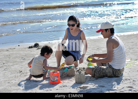 Young family with son making sandcastle on the beach
