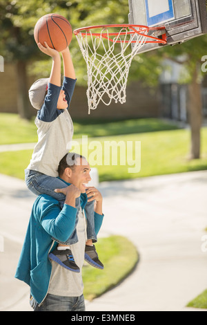Father and son playing basketball in driveway Stock Photo