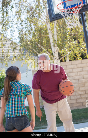 Grandfather and granddaughter playing basketball in driveway Stock Photo