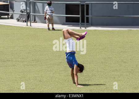 Young girl doing a handstand on the grass at Harbourfront Centre in Toronto Ontario Canada Stock Photo