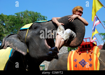 Pattaya, Thailand: Tourist sits in an elephant's trunk at the conclusion of the Nong Nooch Tropical Gardens elephant show Stock Photo