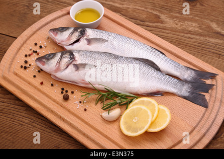 Two fresh sea bass fish on cutting board, top view