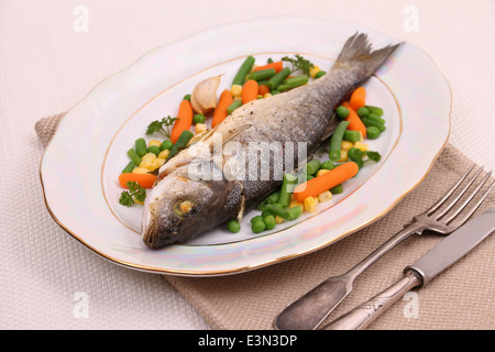 Grilled whole sea bass with vegetables and lemon, close up Stock Photo