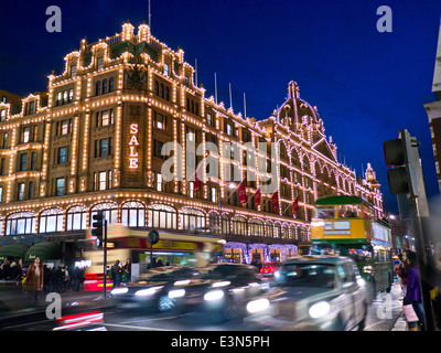 Harrods department store at dusk with lit 'Sale' sign shoppers vintage tour bus and passing taxis Knightsbridge London SW1 Stock Photo