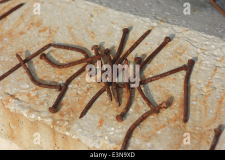 Rusted nails placed on a dappled concrete wall Stock Photo