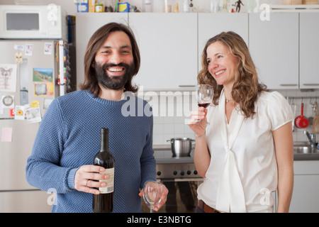Happy couple enjoying red wine in kitchen Stock Photo