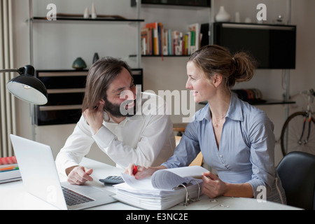 Mid adult couple looking at each other while working at home Stock Photo