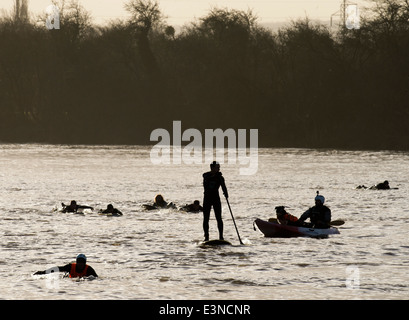 Surfers and canoeists paddle back to the bank after riding the Severn Bore at Minsterworth, Gloucestershire UK 2014 Stock Photo