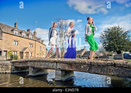Wedding guests cross a stone bridge in the village of Lower Slaughter, Gloucestershire UK Stock Photo