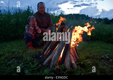 Father and daughter looking at bonfire when celebrating summer solstice in Latvia Stock Photo