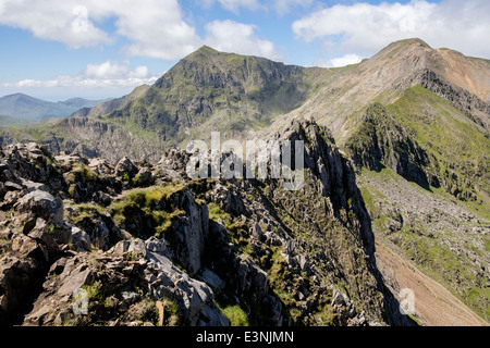 View along Crib Goch ridge scramble to Pinnacles with Crib y Ddysgl and distant Snowdon summit in the horseshoe. Snowdonia National Park Wales UK Stock Photo