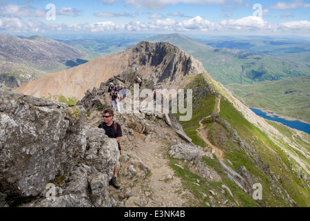 Hikers scrambling on Crib y Ddysgl with view back to Crib Goch ridge on Snowdon Horseshoe in Snowdonia National Park Wales UK Stock Photo