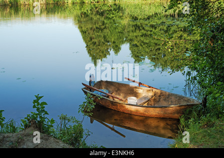 Travel on the silent forest river in the summer. The boat is moored to the river bank. Stock Photo