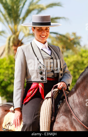 Female rider decked out in traditional flat-topped hat sitting on her horse smiling during Feria del Caballon. Stock Photo