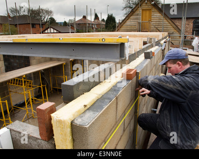 self building house, builder checking level of exterior wall with long spirit level and tape measure Stock Photo