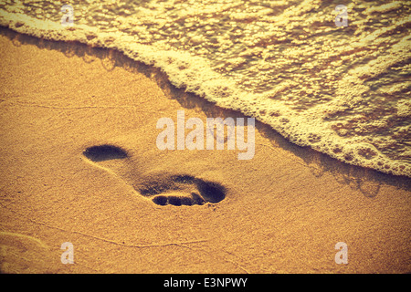 Footprint on sand beach along the edge of sea, vintage retro style. Stock Photo