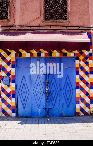 Blue garage door surrounded by multi coloured ceramic tiles on a building in Marrakech, Morocco Stock Photo