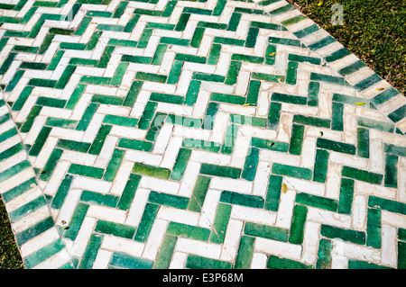 Garden path made from green and white rectangular ceramic tiles, laid in a herringbone pattern. Stock Photo