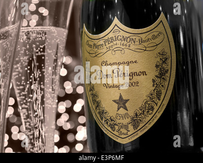 DOM PERIGNON CHAMPAGNE Bottle and freshly poured glasses of 2002 Dom Perignon luxury vintage champagne with lights in background retro partial B&W Stock Photo