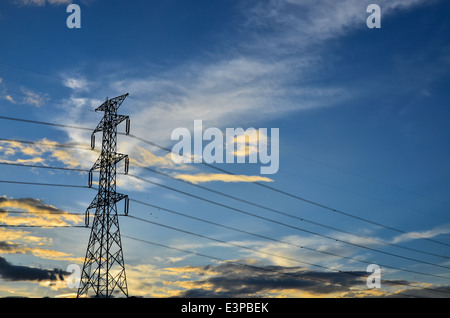 power tower silhouetted against blue sky and light clouds Stock Photo