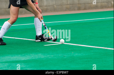 Female field hockey player puts the ball in play after a foul Stock Photo