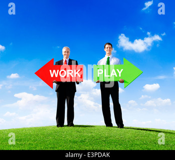 Two Businessmen Holding Contrasting Arrows for Work and Play Stock Photo