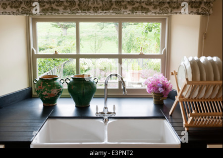 Belfast sink by Magnet with wooden plate rack and window with garden views Stock Photo