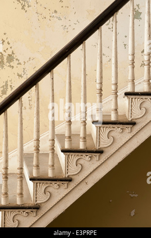 Carved detail on steps of old staircase with cracked wall paint Stock Photo