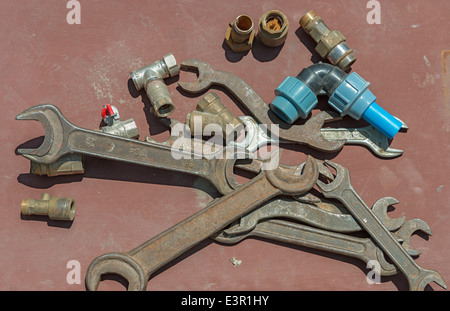Many rusty wrenches and valves on light brown background. Stock Photo