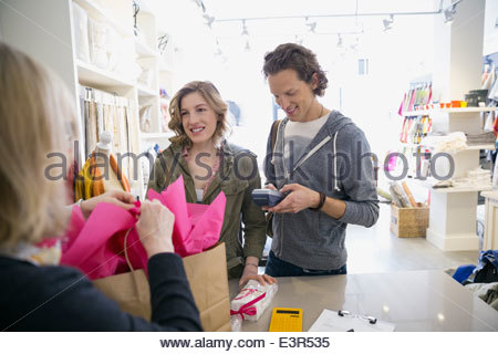 Couple using credit card reader in shop