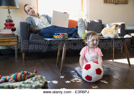 Father with laptop watching baby daughter play