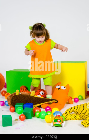 Little caucasian girl is standing among toys Stock Photo